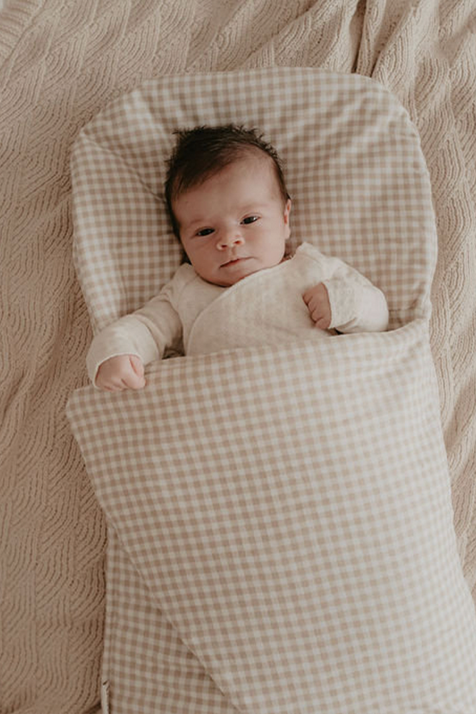 baby sleeping in beige gingham wool wrap