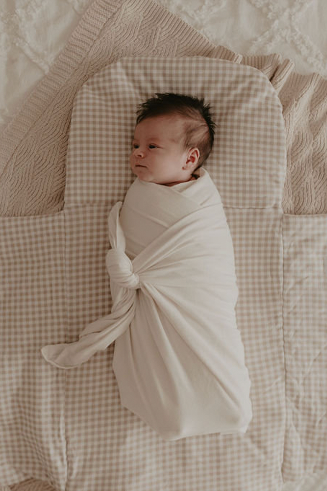 Baby swaddled and laying on top of gingham Bundl wool wrap