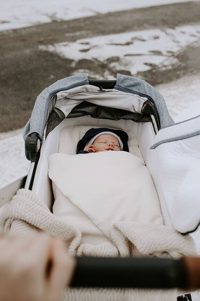 Baby sleeping in Bundl wool wrap in pram in the snow