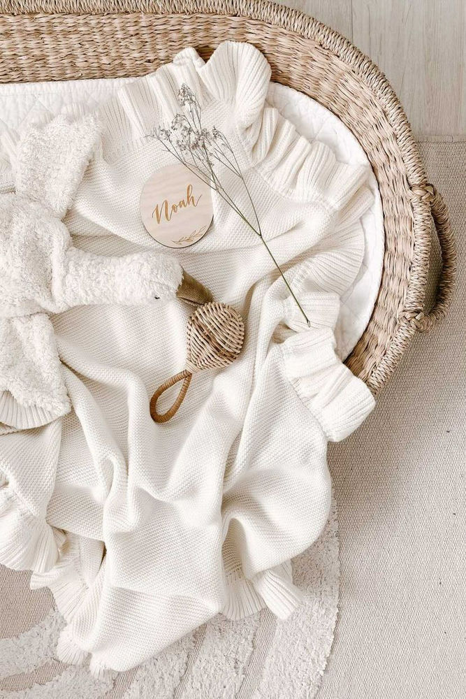knitted white baby blanket with white goose comforter toy in straw change basket