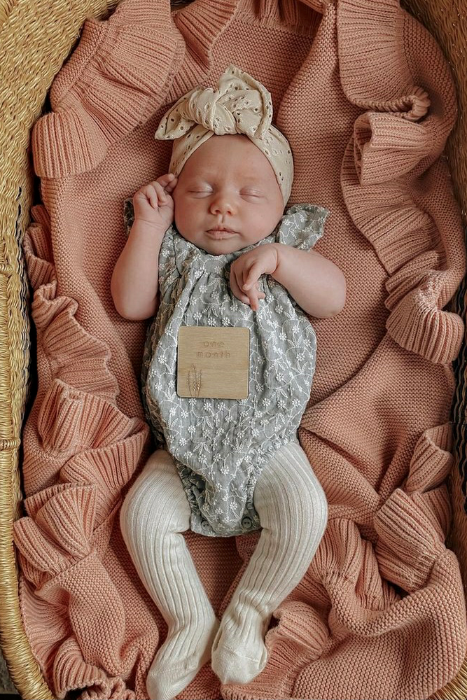 baby sleeping in bassinet on pink frill knitted blanket