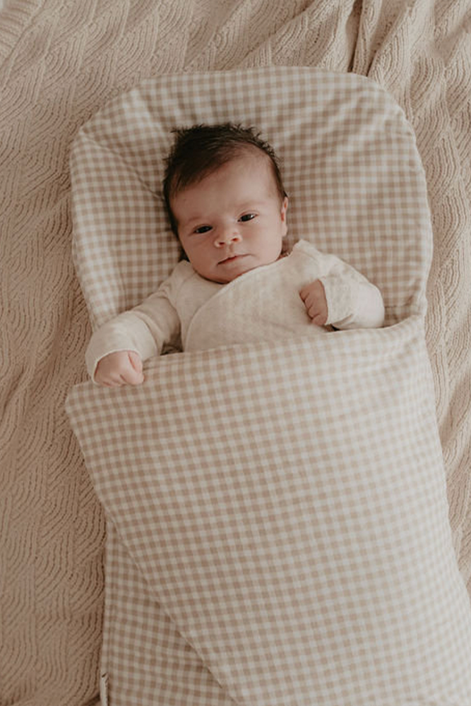 baby sleeping in beige gingham wool wrap 