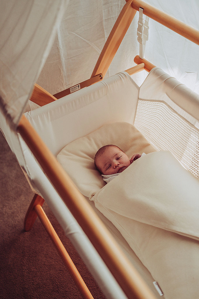 Baby sleeping in Bundl wool wrap in bassinet