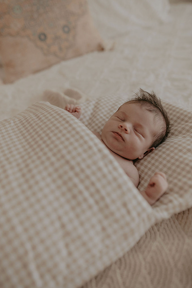 Baby sleeping in  gingham Bundl wool wrap 