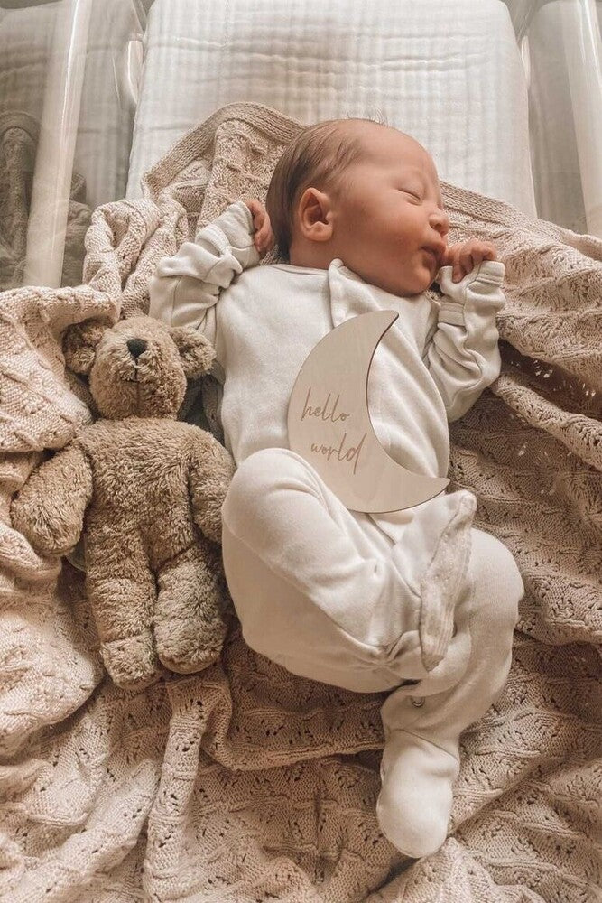 new born baby on beige blanket with teddy bear