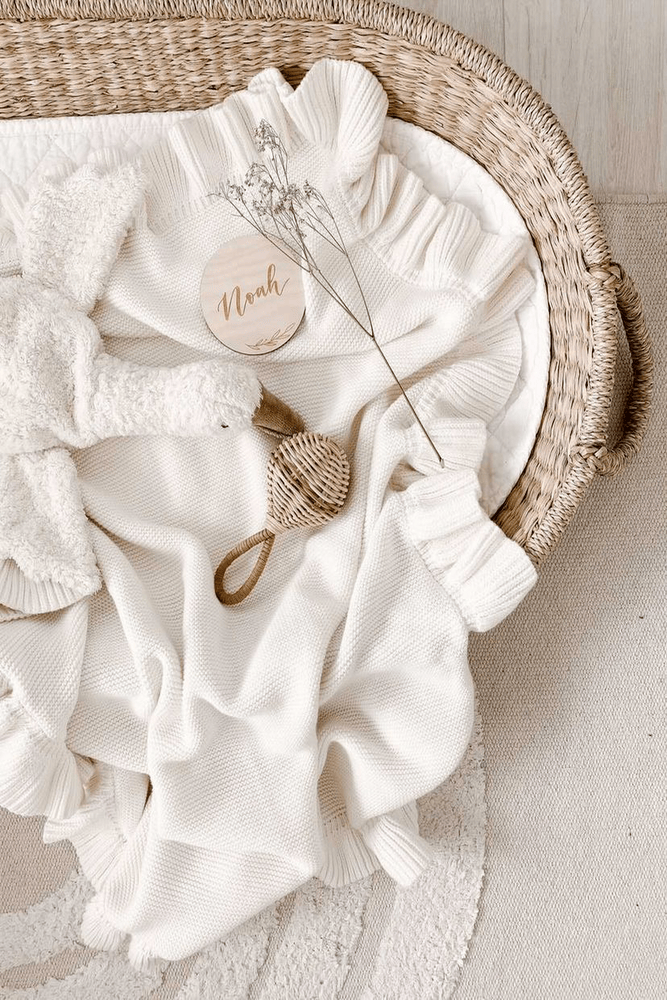knitted white baby blanket with white goose comforter toy in straw change basket